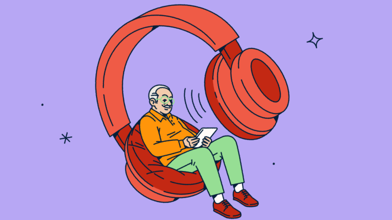 A person looking at a tablet while sitting in one side of a giant pair of headphones.