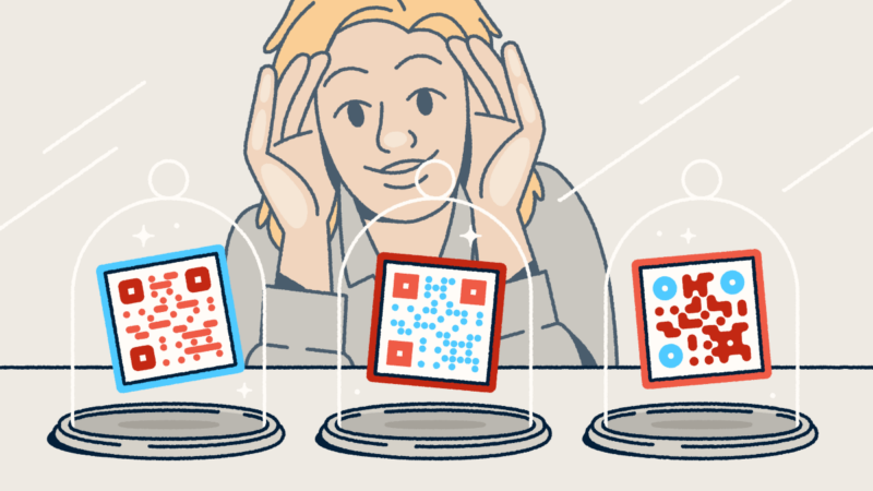 A person looking through a store-front window at three different QR codes on display in glass cloches.